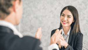 Women smiling while man congratulatorily claps in front of her