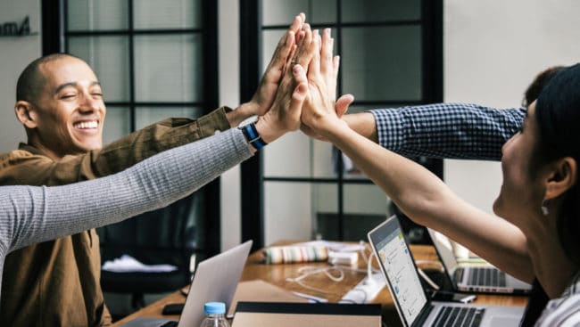 Peer recognition moment being displayed as a high five over employees desks