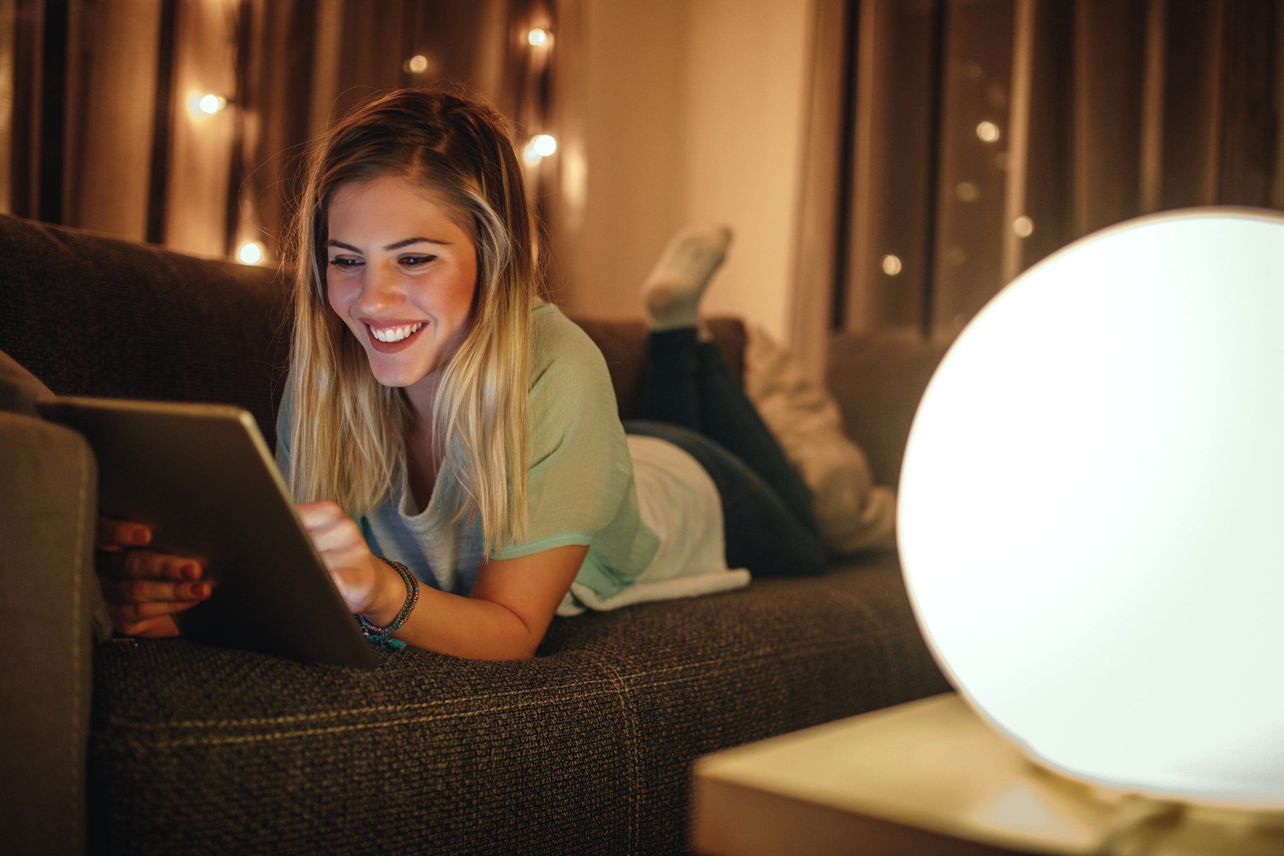 Attractive girl lying on sofa and using tablet.