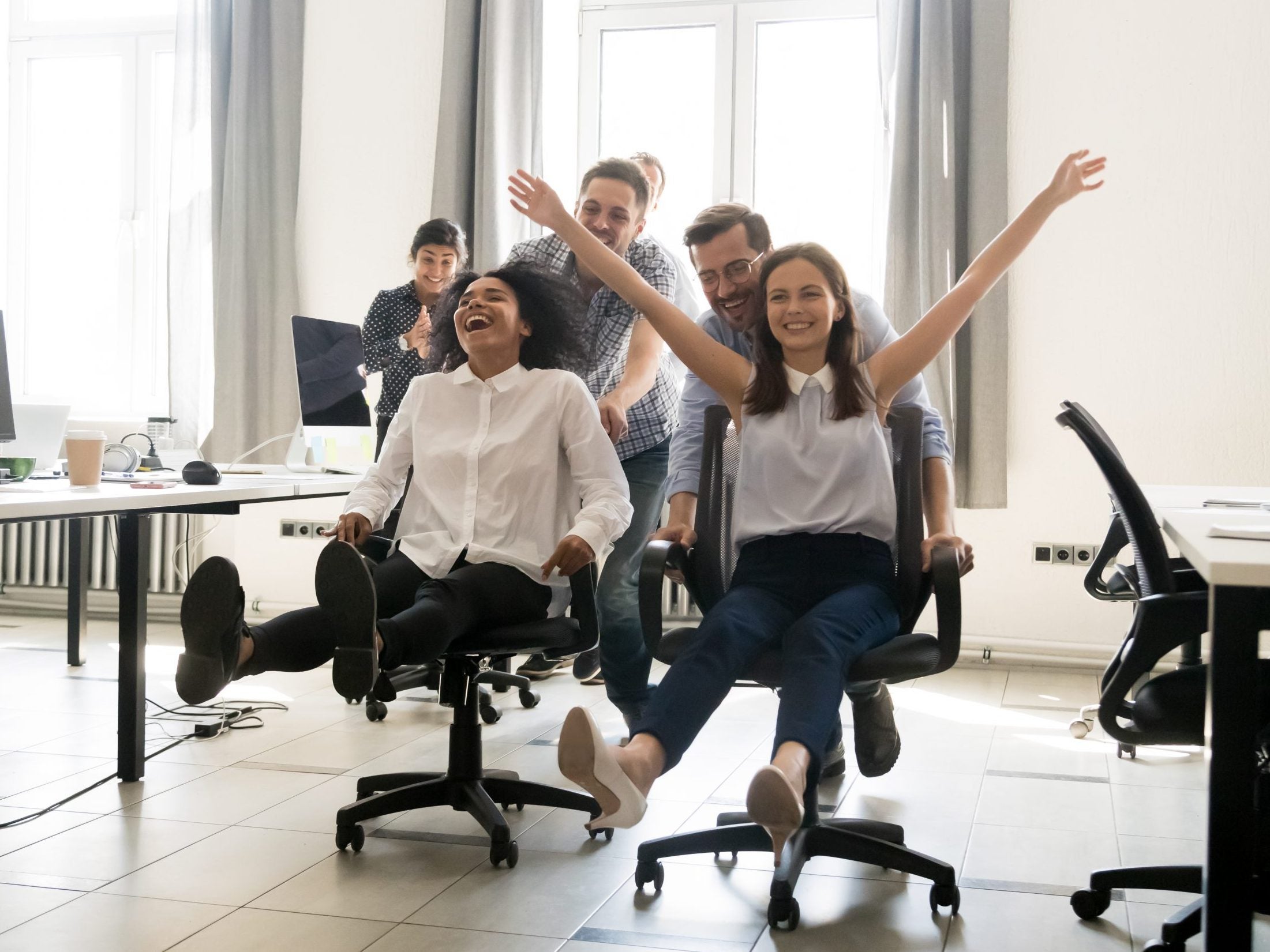 Happy,Multiracial,Colleagues,Group,Having,Fun,Together,,Riding,On,Chairs