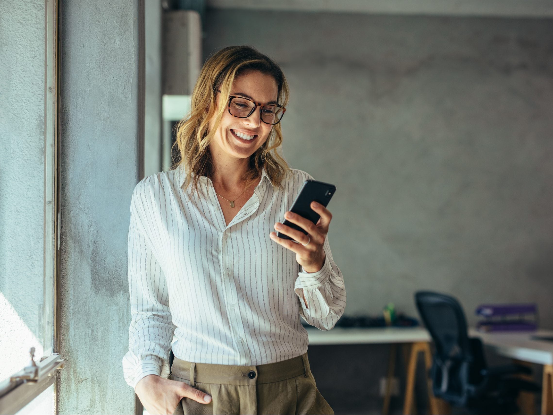 Smiling,Businesswoman,Using,Phone,In,Office.,Small,Business,Entrepreneur,Looking Smiling,Businesswoman,Using,Phone,In,Office.,Small,Business,Entrepreneur,Looking