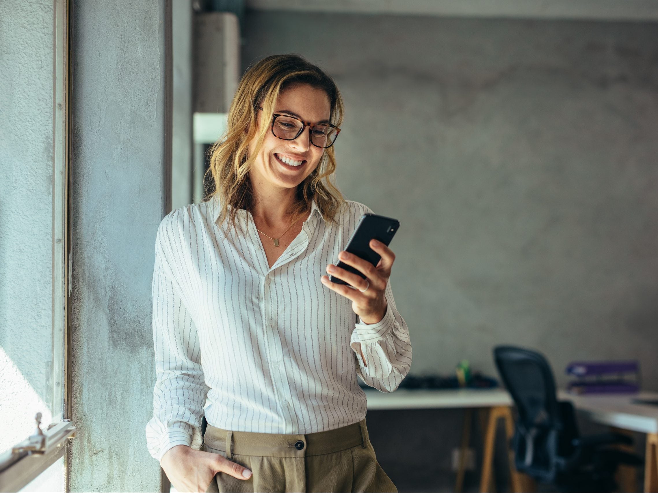 Smiling,Businesswoman,Using,Phone,In,Office.,Small,Business,Entrepreneur,Looking