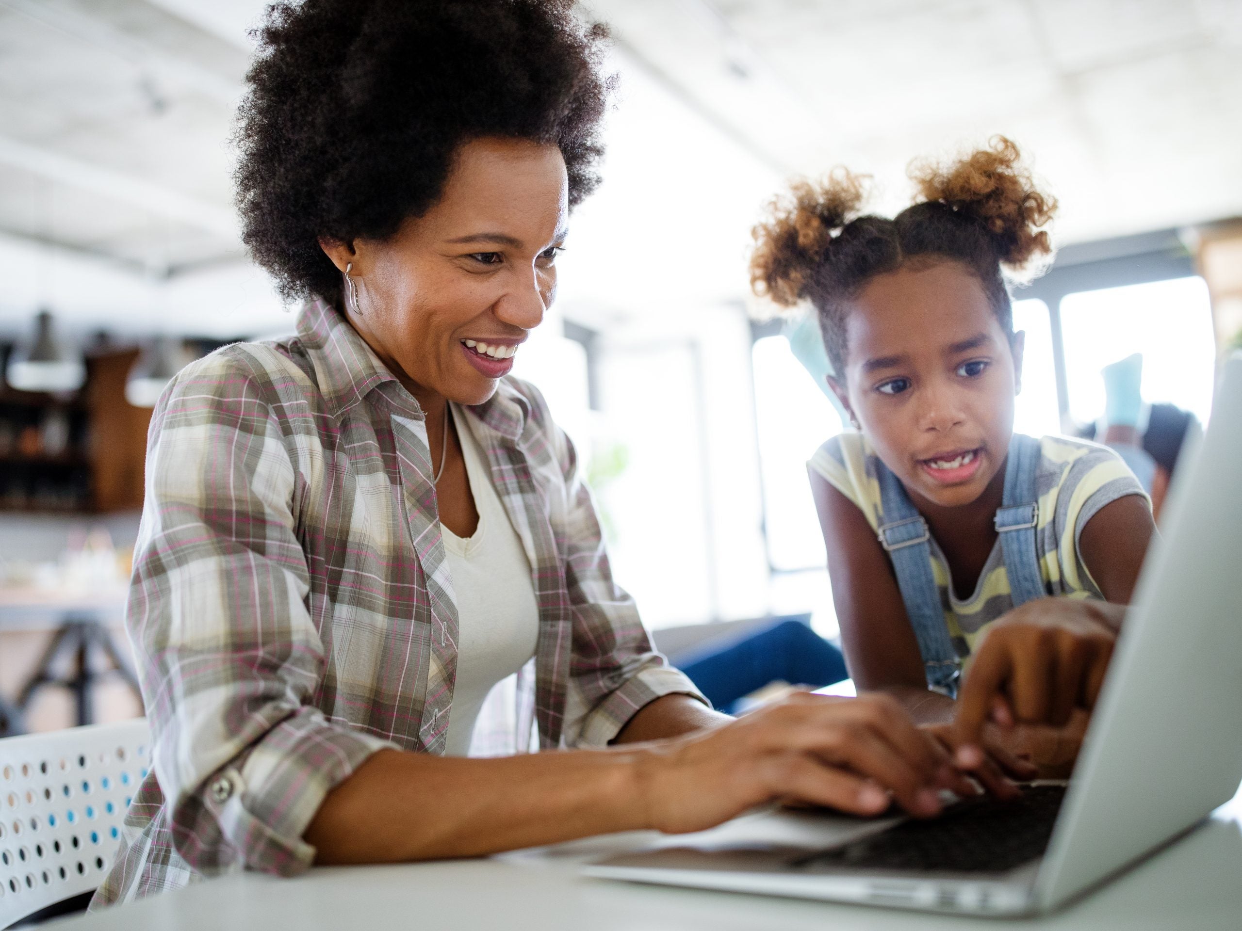 Happy family mother and child daughter at home working on the computer