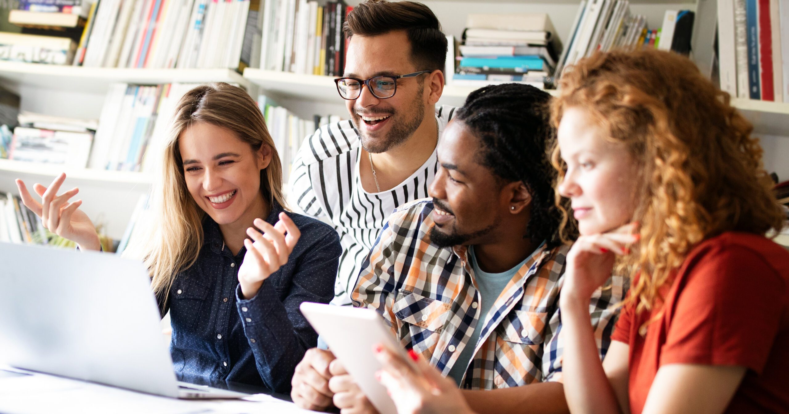 Group of 4 young proplr happily looking at a laptop screen