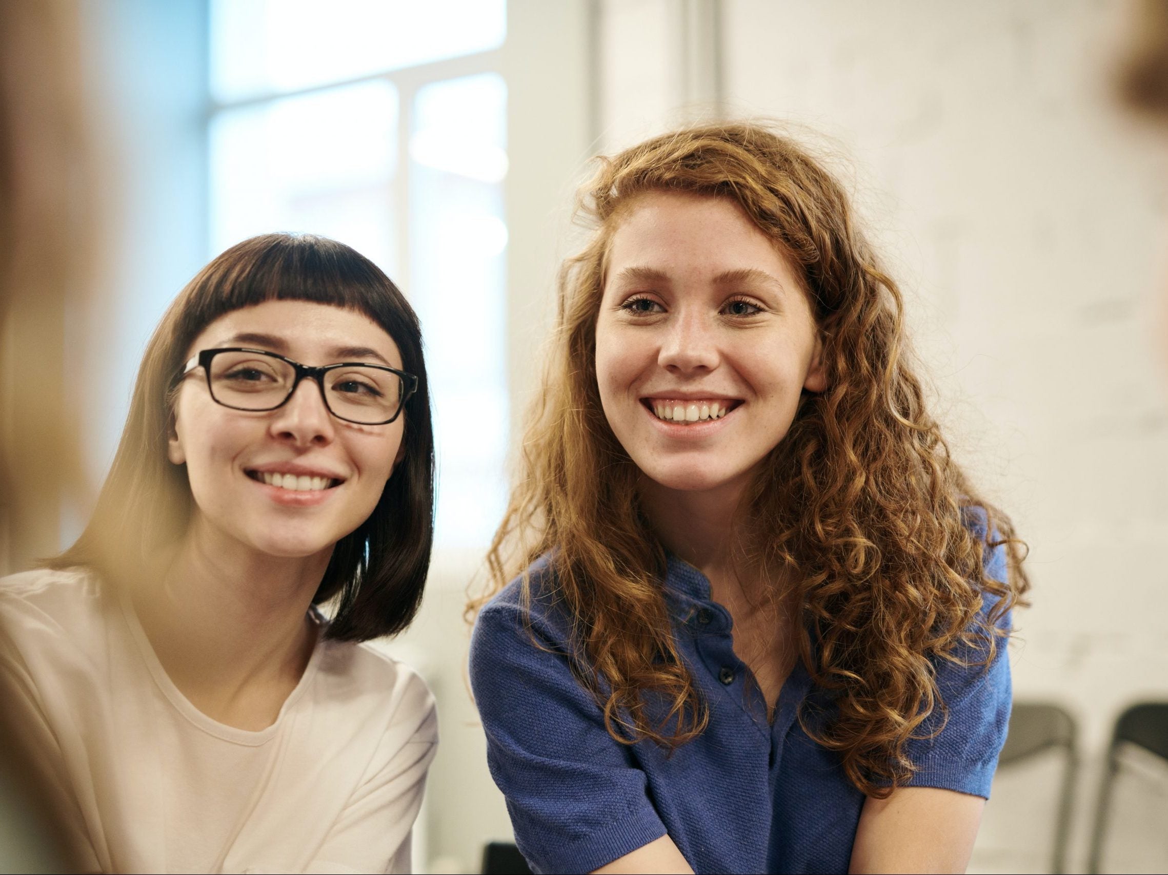 Two smiling women sitting next to eachother