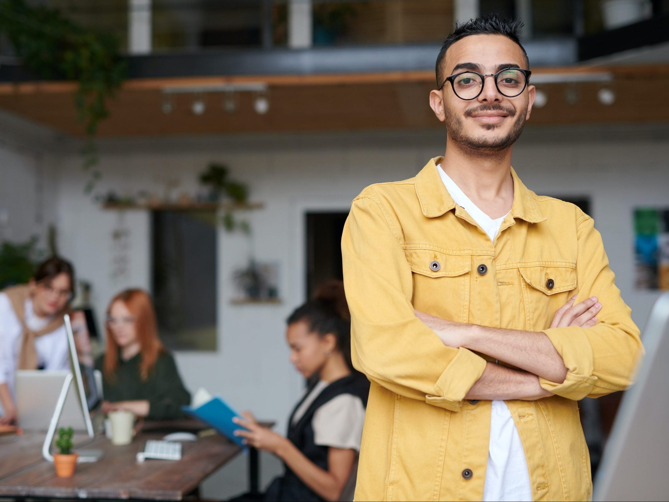 Man in yellow shirt and glasses smirking and looking at the viewer