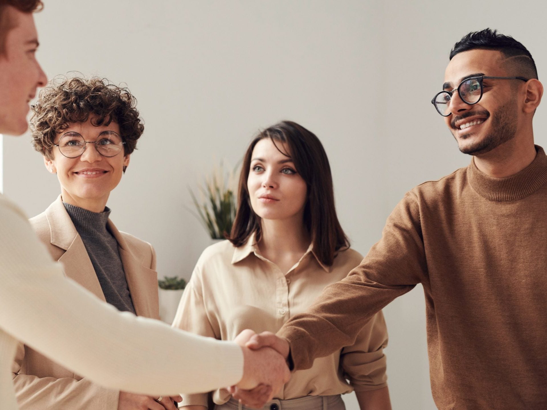 Two men shaking hands while two women smile as they watch