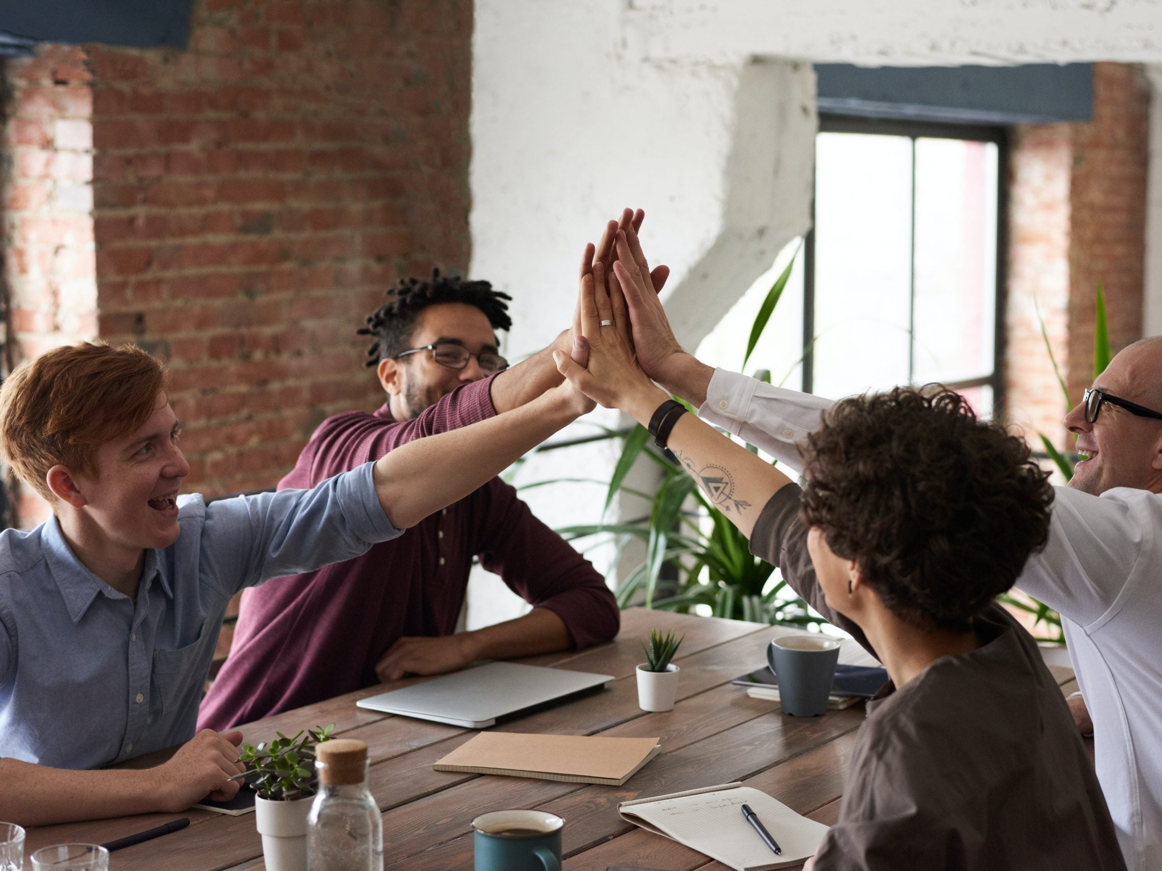 4 people at a table high fiving eachother in the center