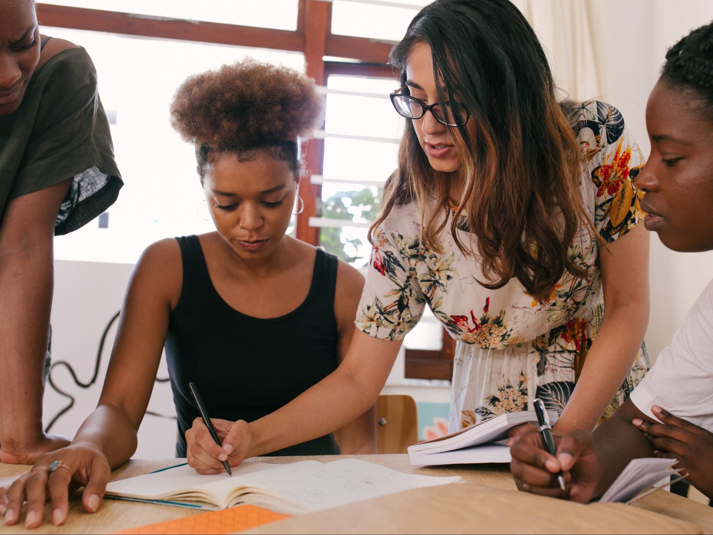 4 people collaborating in a notebook at the center of the table