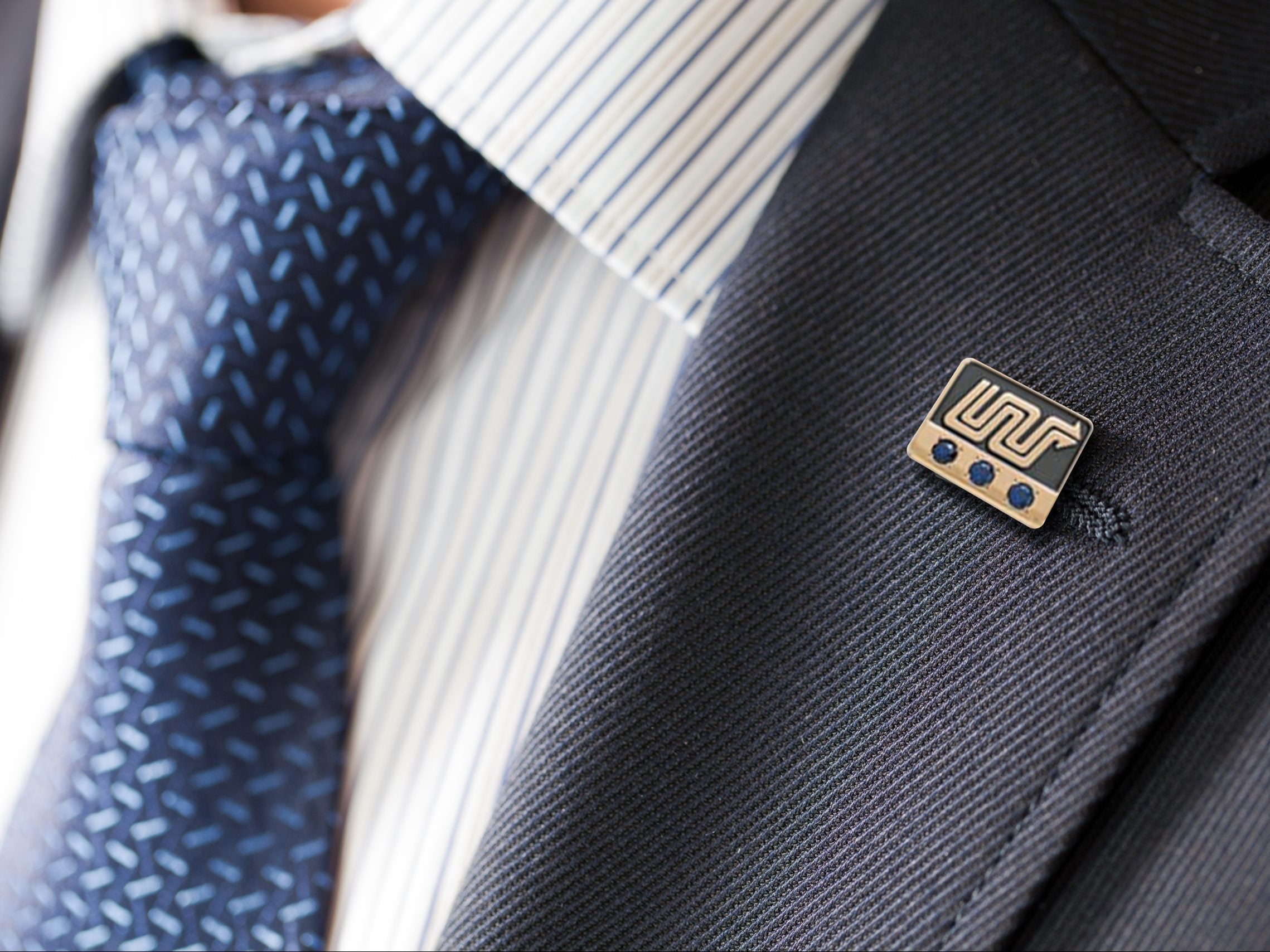 badge on the lapel of his jacket men's shirt with a blue tie