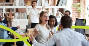 Office setting of excited people clapping and cheering for a fellow employee
