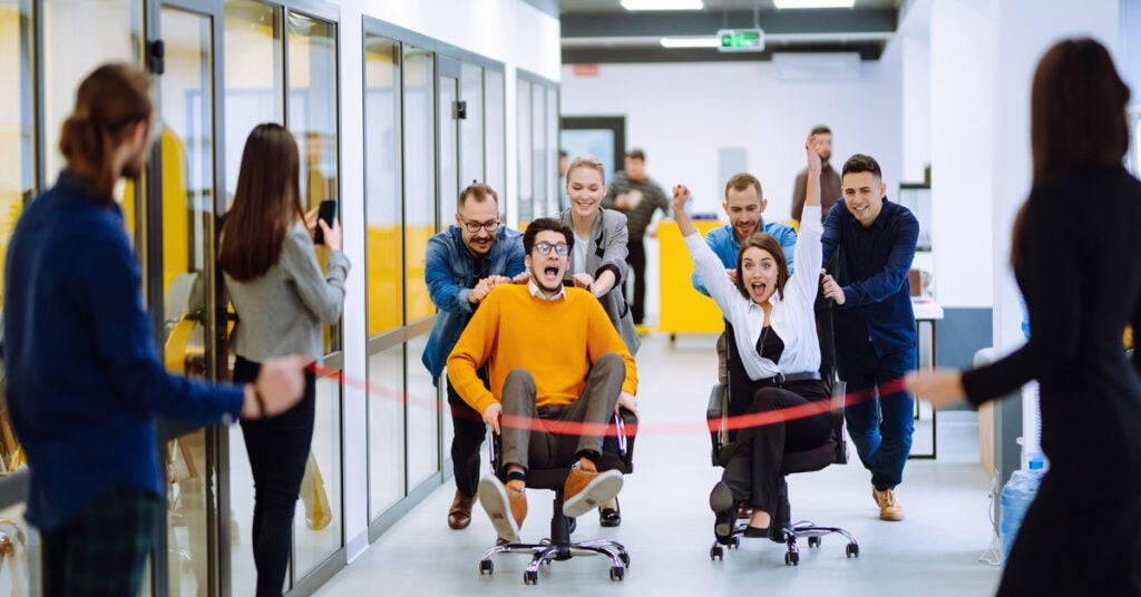 Employees Racing in Office Chairs at Work