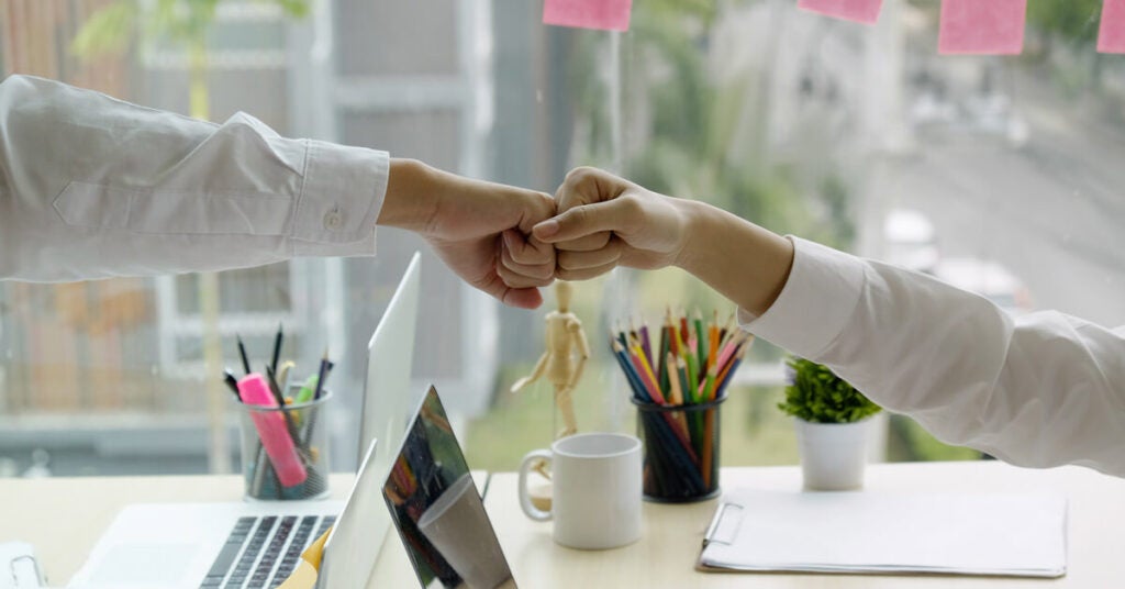 Two engaged employees fist bumping