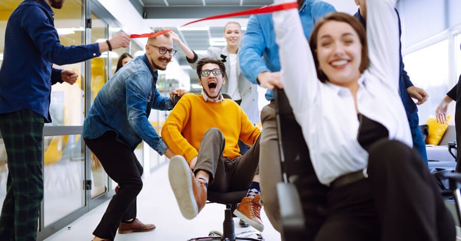 Multiple engaged employees racing office chairs and having fun 