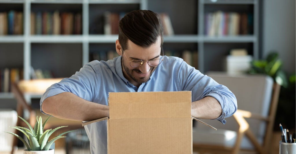 Happy man at desk opening box