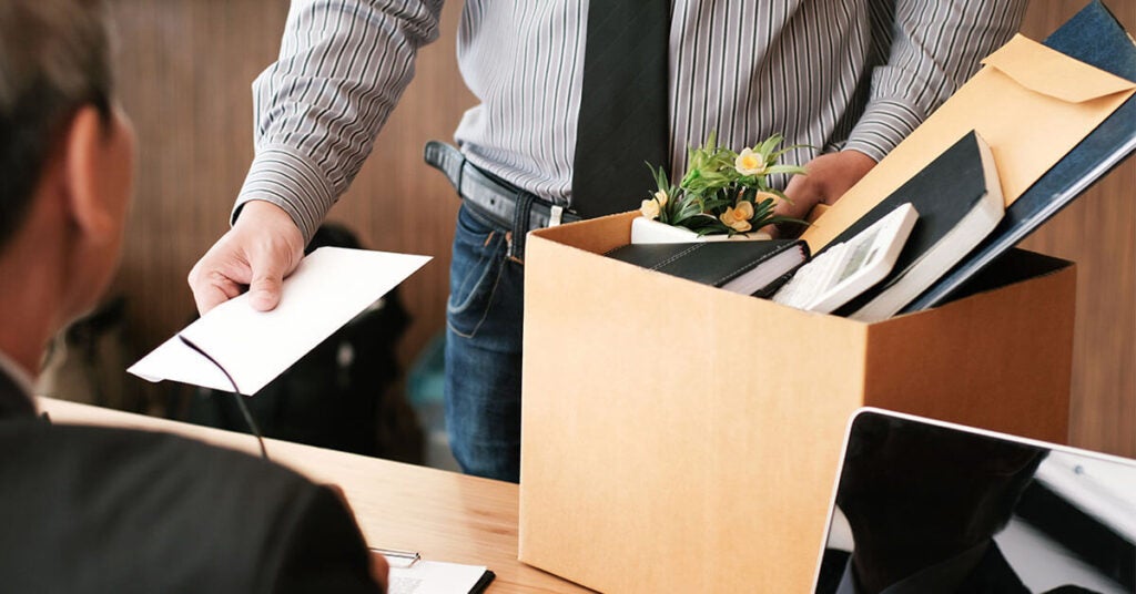 Man handing in resignation letter with box of office supplies