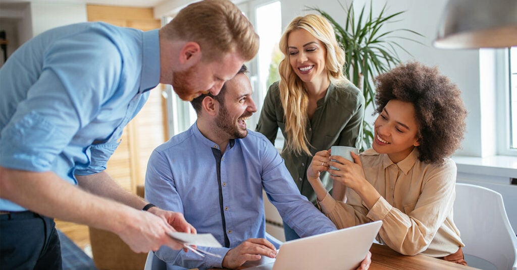 Happy-Employees-Gathered-Around-a-Computer-With-A-Social-recognition-Program