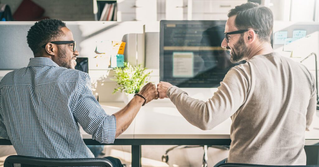 Two engaged employees fist bumping