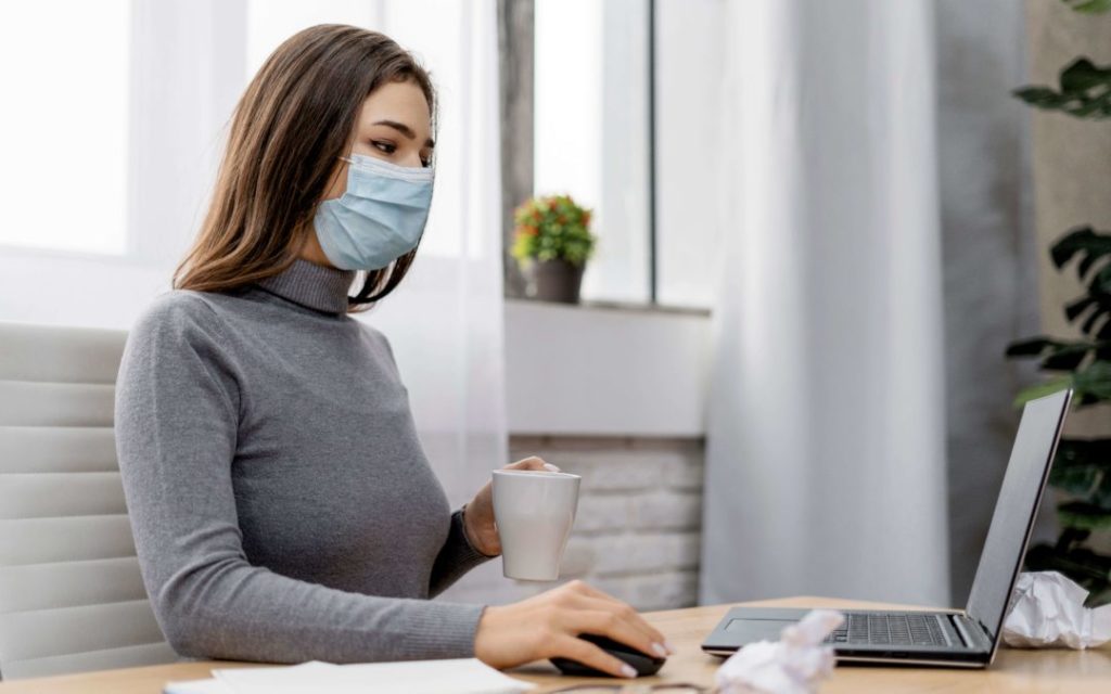 woman wearing mask sitting a laptop