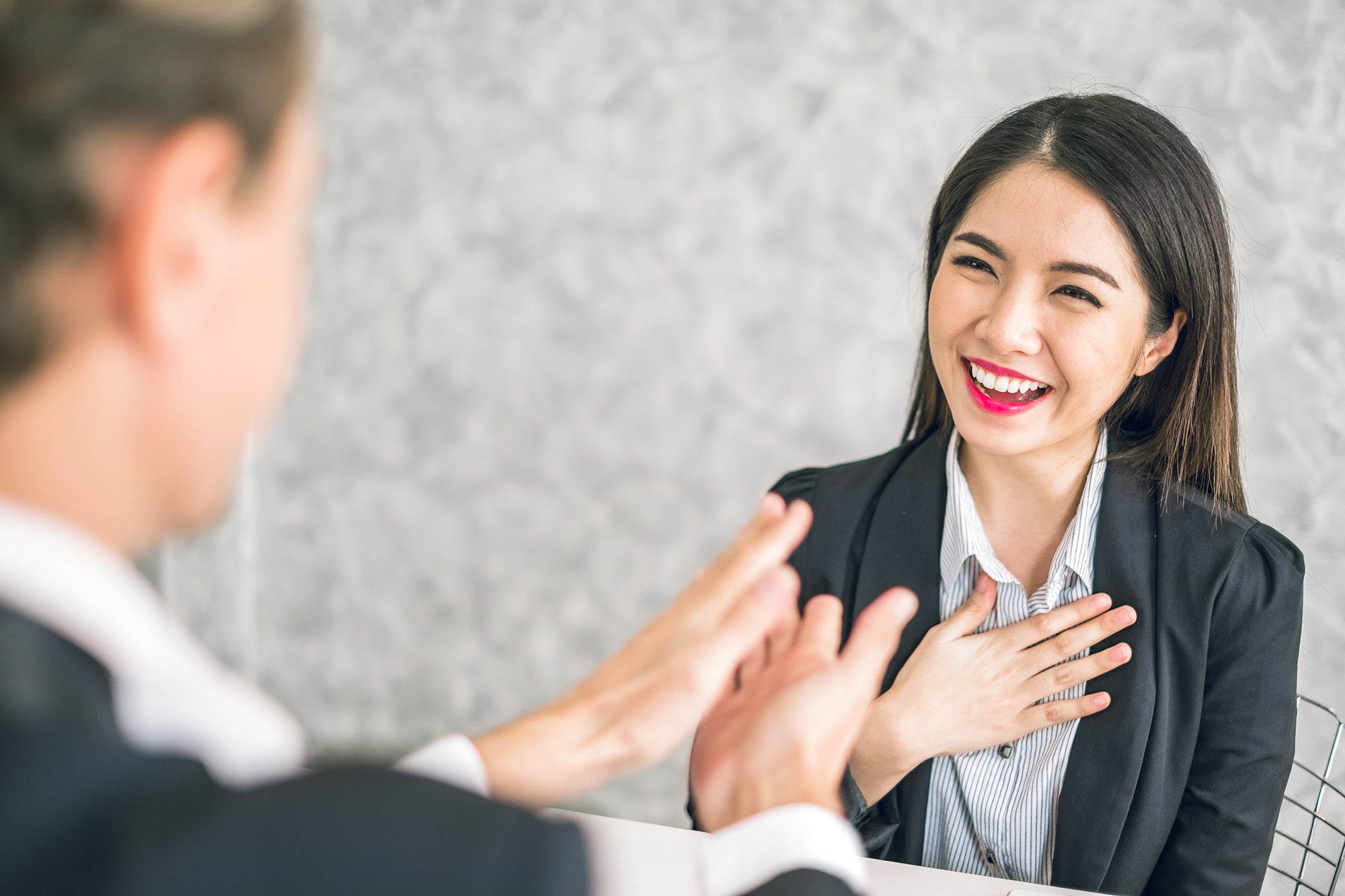 Boss/Business man employer admires young Asian business woman/staff/employee by thumb up and clap with smiling face for her success and good/best in work and recognition/appreciate.