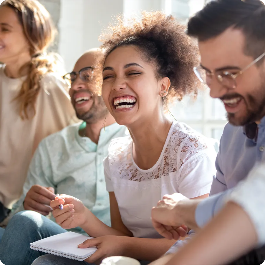 Four people sit in a brightly lit room and are smiling. 