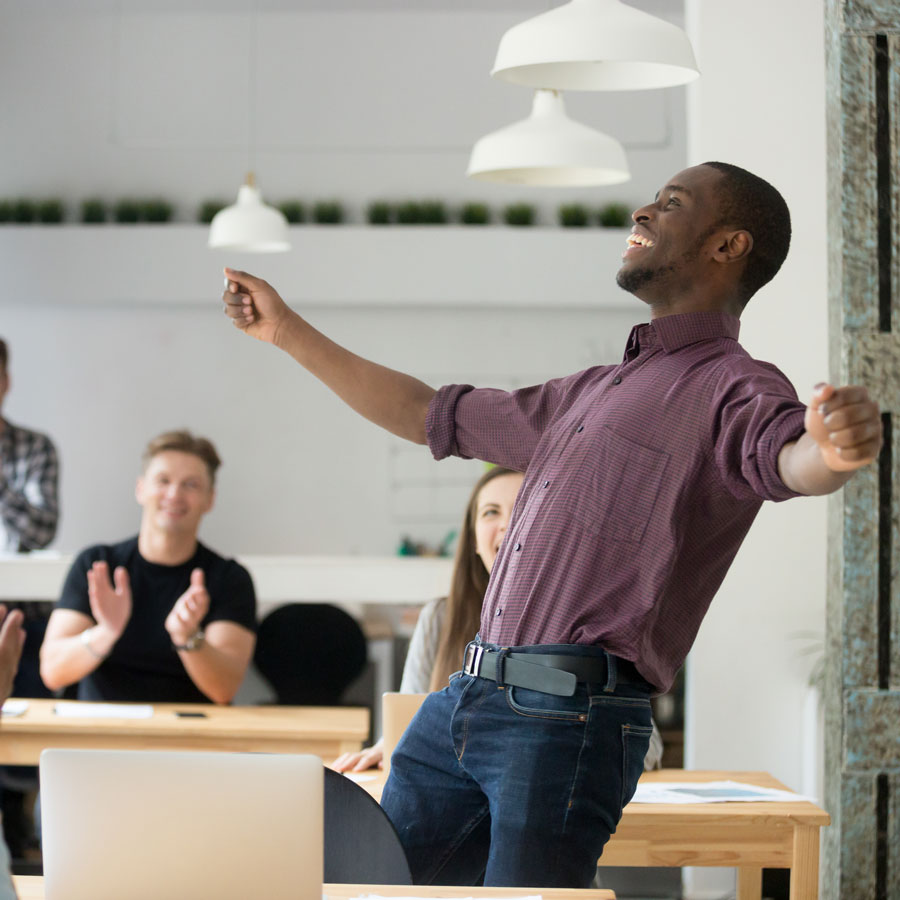 A man celebrates an achievement before his excited peers.