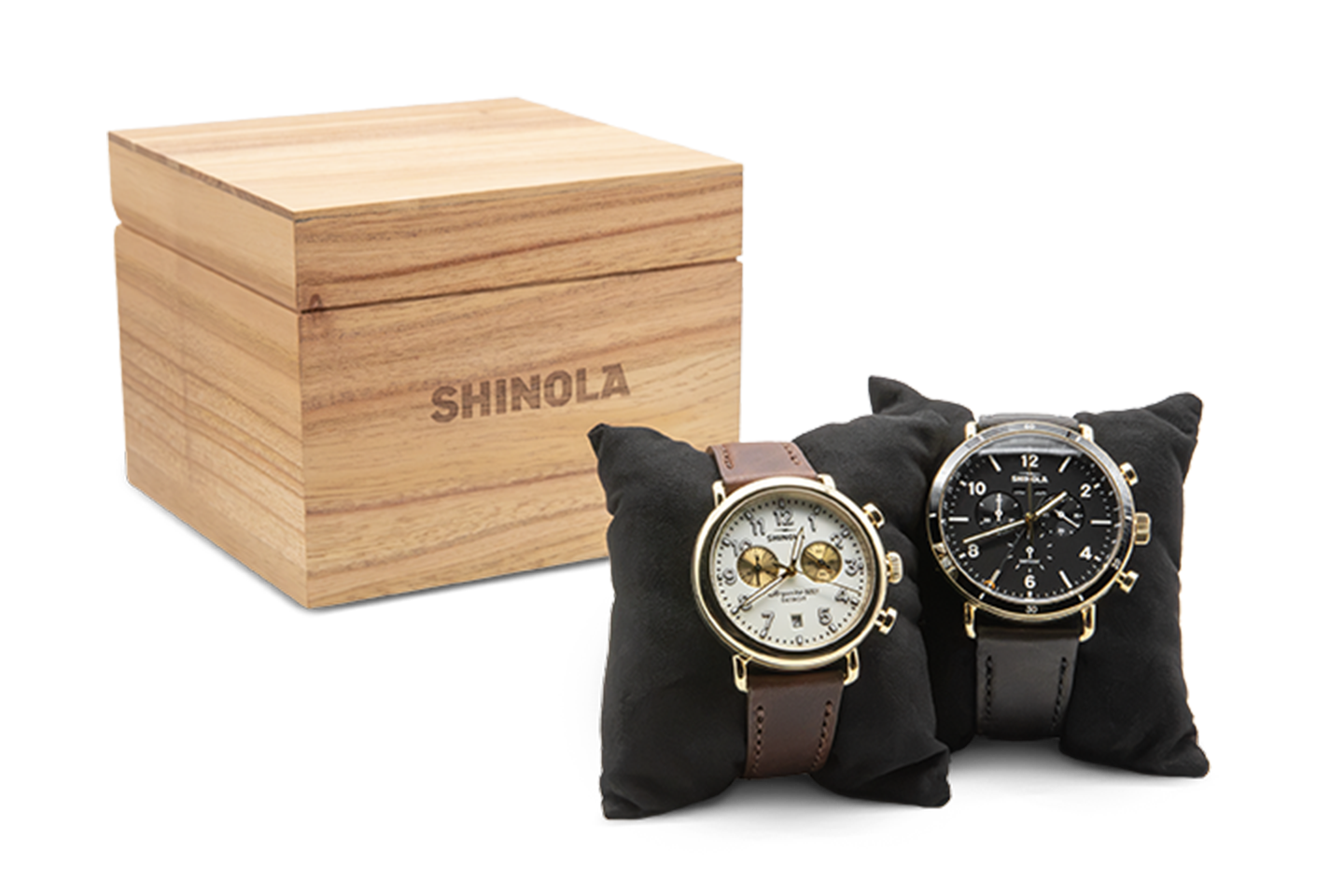 Two Shinola watches strapped on the small black pillows with a wooden Shinola box in the background