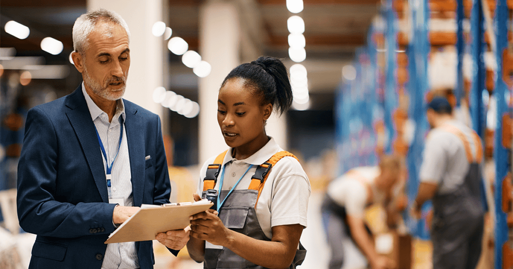 Older man and younger woman discussing work in factory setting