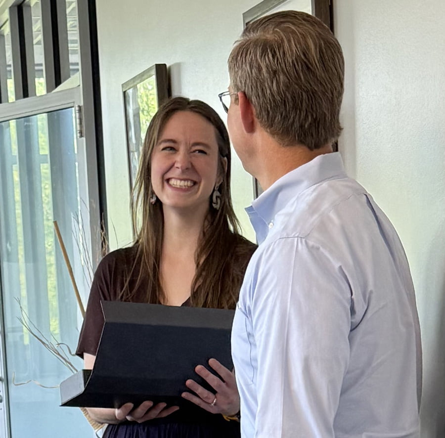 Two colleagues share a service award during a recognition moment
