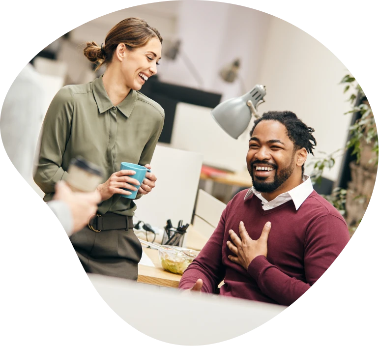 Two colleagues talking and laughing at a desk