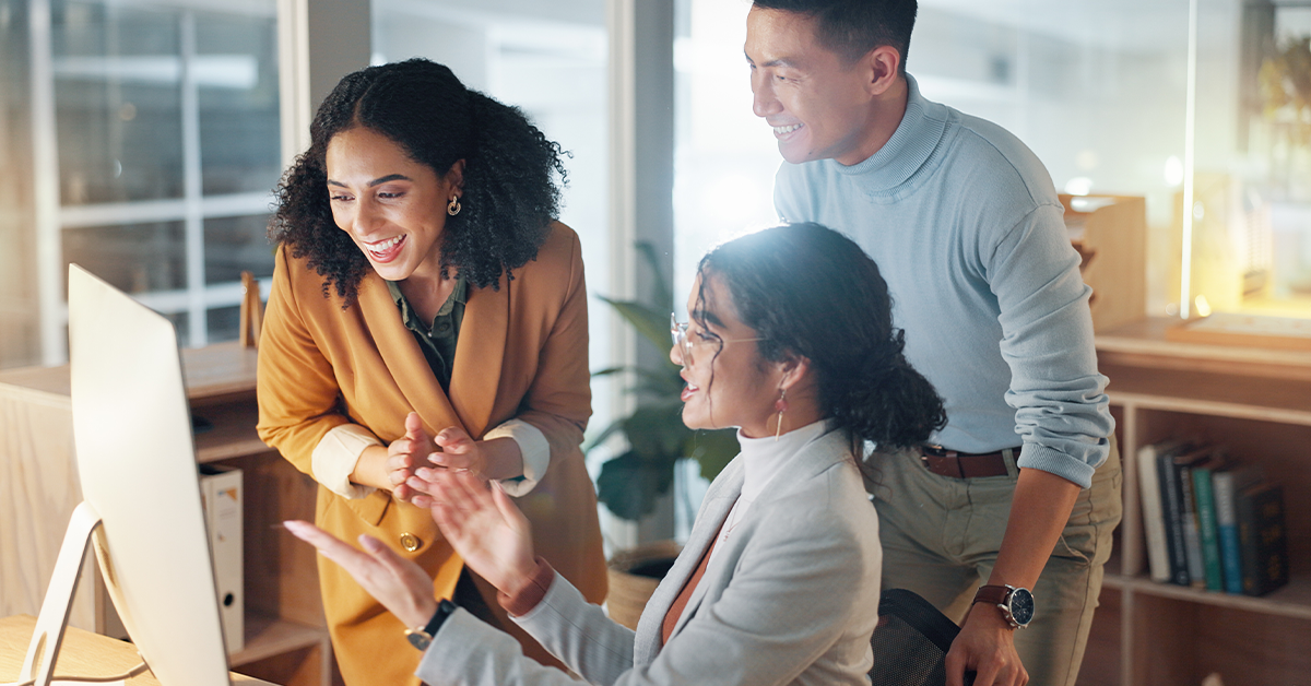 Happy employees gathered around a computer