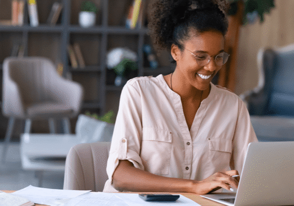 happy woman smiling at her laptop at home