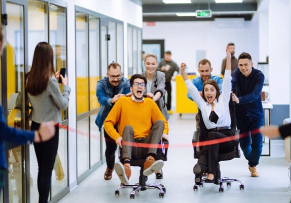Employees Racing in Office Chairs at Work