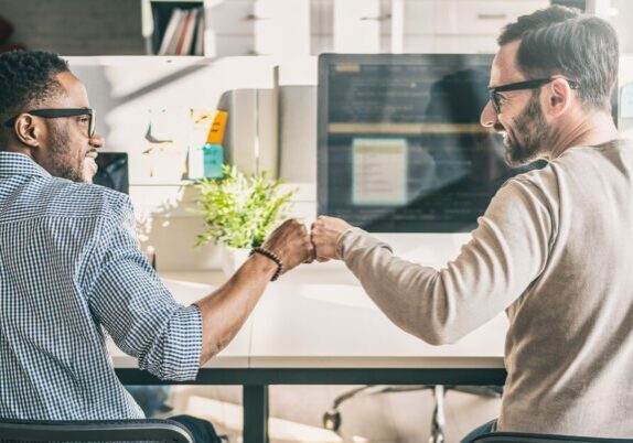Two engaged employees fist bumping