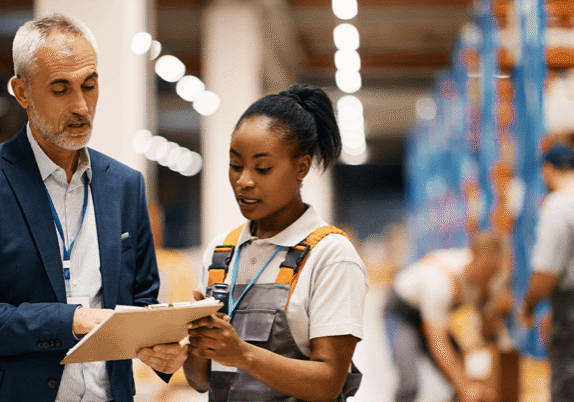 Older man and younger woman discussing work in factory setting