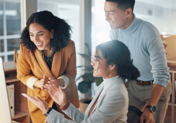 Happy employees gathered around a computer