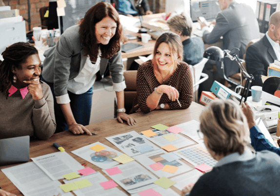 group of happy employees gathered around table